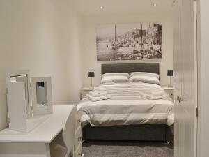 a white bedroom with a bed and a mirror at Sea Blue Cottage in Scarborough