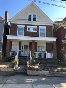 a red brick house with a white porch at Highland Park Pittsburgh in Pittsburgh