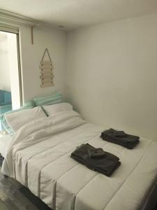 een wit bed met twee zwarte handdoeken erop bij Bord de mer : studio avec salon d'été à Sausset in Sausset-les-Pins