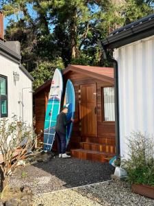 a person standing next to two surfboards on a building at Jo and Lee Kids House in Seogwipo