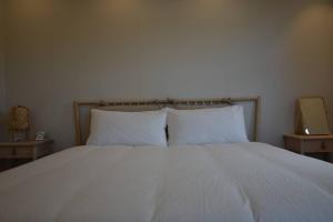 una camera con un letto bianco con due comodini di Jo and Lee Kids House a Seogwipo