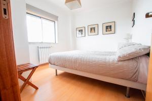 een witte slaapkamer met een bed en een raam bij Villa7pax baby friendly Near Dino Park&Beaches in São Bartolomeu