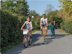 a man and a woman riding bikes down a road at Mobil confort 2 chambres 1 sd 35m2 à la teste in La Teste-de-Buch