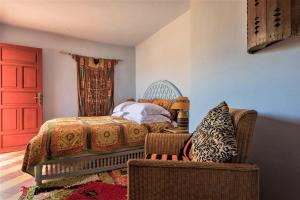 1 dormitorio con cama, silla y puerta roja en Riad Jardin Des Biehn en Fez