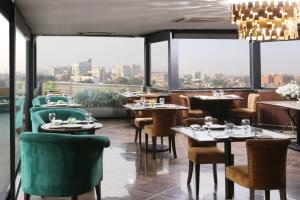 un restaurante con mesas, sillas y ventanas grandes en Four Points by Sheraton Lahore, en Lahore