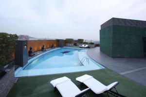 a swimming pool on top of a building with two chairs at Four Points by Sheraton Lahore in Lahore