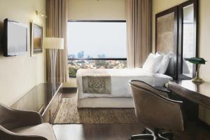 a hotel room with a bed and a desk and a window at Four Points by Sheraton Lahore in Lahore