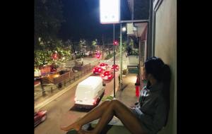 a woman sitting on a window sill looking out at a street at Hotel MM Dateo in Milan