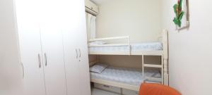 ein kleines Zimmer mit weißen Schränken und einem Etagenbett in der Unterkunft Conforto a 300m da Praia do Forte in Cabo Frio