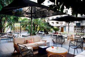 un patio con divano, tavoli e sedie. di AC Hotel Victoria Suites by Marriott a Barcellona