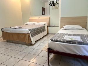 a room with two beds and a tiled floor at Hotel Taquaral in Campinas