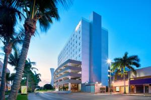 a tall building with palm trees in front of it at Aloft Cancun in Cancún