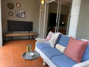 sala de estar con sofá azul y TV en Endonini House en Nelspruit