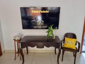 a table and a chair with a tv on a wall at Casa Faisão in Nova Lima