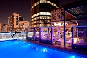 uma piscina no último piso com cadeiras roxas e um edifício em Courtyard by Marriott World Trade Center, Abu Dhabi em Abu Dhabi