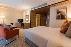 Cette chambre comprend un grand lit et une chaise. dans l'établissement Courtyard by Marriott World Trade Center, Abu Dhabi, à Abu Dhabi