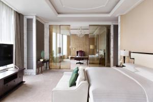 Shunde Marriott Hotel في شوند: غرفة نوم بسرير ابيض كبير وغرفة معيشة