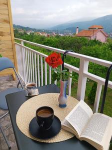 a table with a cup of coffee and a book at Apartman HeLena in Soko Banja
