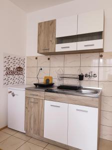 a kitchen with white cabinets and a sink and a refrigerator at Apartman HeLena in Soko Banja