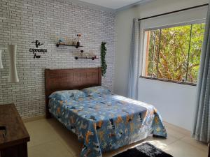 a bedroom with a bed with a blue comforter and a window at Casa Faisão in Nova Lima