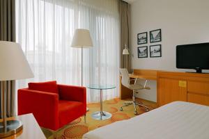 ブダペストにあるコートヤード バイ マリオット ブダペスト シティ センターの赤い椅子とテレビが備わるホテルルームです。