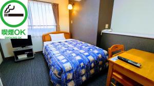 ein Hotelzimmer mit einem Bett, einem Schreibtisch und einem Tisch in der Unterkunft Azu Garden Nippombashi in Osaka