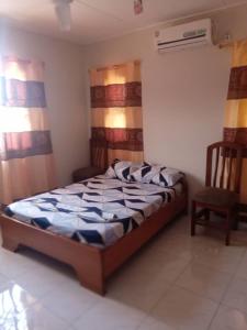 a bedroom with a bed and a chair at Spintex Villas - Available for Long Term Rentals in Ablekuma