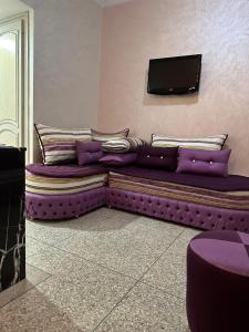un sofá púrpura con almohadas y TV de pantalla plana en NADIA BELVUE 3, en Meknès