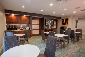 a waiting room with tables and chairs and a kitchen at Residence Inn Cincinnati North West Chester in West Chester