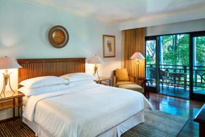 a bedroom with a large white bed and a balcony at Sheraton Senggigi Beach Resort in Senggigi
