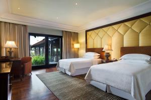 a hotel room with two beds and a desk at Sheraton Senggigi Beach Resort in Senggigi