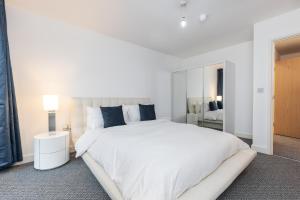 a white bedroom with a large white bed with blue pillows at Right Place in London
