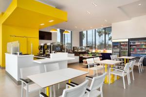 a library with white tables and chairs and a yellow wall at The Viv Hotel, Anaheim, a Tribute Portfolio Hotel in Anaheim