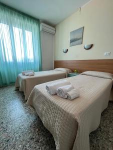 a room with three beds with towels on them at Hotel Valente in Ortona