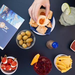 a table with plates of food and a person holding a sandwich at Hotel Rudy in Riva del Garda