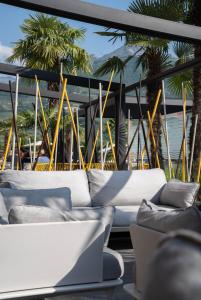 a group of couches on a balcony with palm trees at Hotel Rudy in Riva del Garda