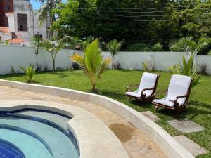 2 Stühle und ein Pool im Hof in der Unterkunft Villa Macheo in Mombasa
