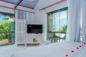 a bedroom with a bed and a tv and a balcony at Villa Pantai Milagres Exclusive Hotel in São Miguel dos Milagres