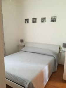 un letto bianco in una stanza con immagini appese al muro di Appartamento Bellavista a Castiglioncello