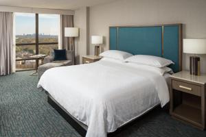 a hotel room with a large bed and a large window at Sheraton Dallas Hotel by the Galleria in Dallas