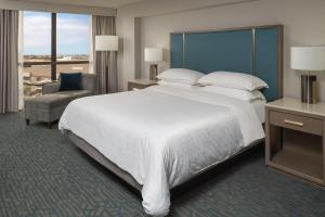 a hotel room with a large bed and a chair at Sheraton Dallas Hotel by the Galleria in Dallas