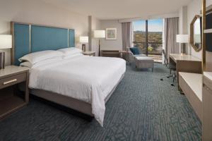 a hotel room with a large bed and a desk at Sheraton Dallas Hotel by the Galleria in Dallas