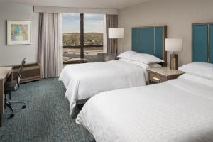a hotel room with two beds and a desk at Sheraton Dallas Hotel by the Galleria in Dallas