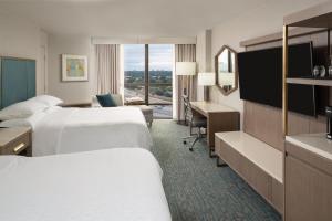 a hotel room with two beds and a television at Sheraton Dallas Hotel by the Galleria in Dallas