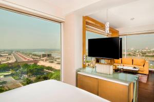 a bedroom with a large window with a flat screen tv at Renaissance Lucknow Hotel in Lucknow