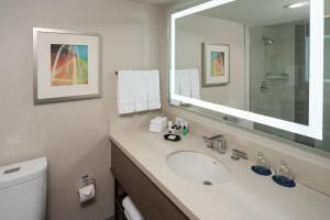 a bathroom with a sink and a mirror and a toilet at Sheraton Dallas Hotel by the Galleria in Dallas