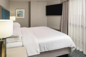 a hotel room with a bed and a flat screen tv at Sheraton Dallas Hotel by the Galleria in Dallas