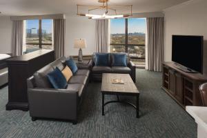 a living room with a couch and a tv at Sheraton Dallas Hotel by the Galleria in Dallas