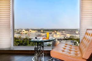 um quarto com uma mesa e duas cadeiras e uma grande janela em Renaissance Lucknow Hotel em Lucknow