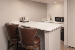 a kitchen with a counter with two chairs and a microwave at Sheraton Dallas Hotel by the Galleria in Dallas
